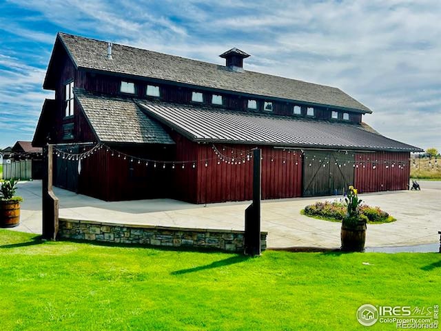 exterior space with a standing seam roof, a barn, a yard, and an outbuilding