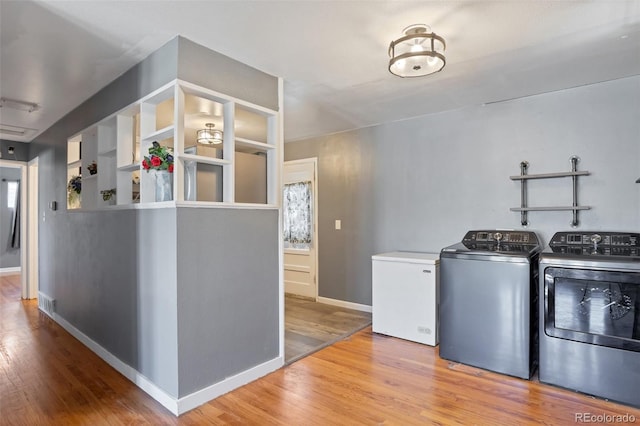 laundry room with washer and clothes dryer and light hardwood / wood-style flooring