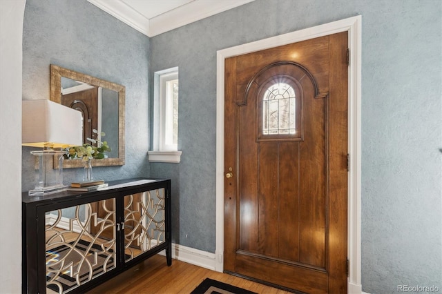 foyer entrance with crown molding, baseboards, and wood finished floors