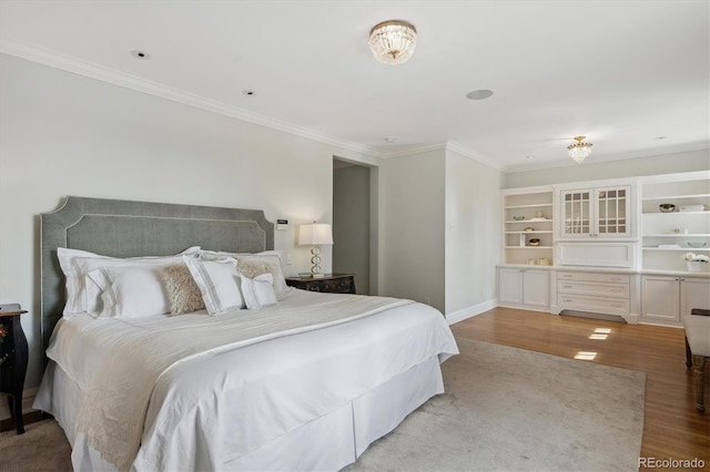 bedroom featuring light wood finished floors, baseboards, and crown molding