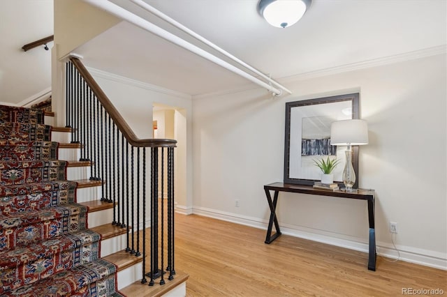 staircase with baseboards, wood finished floors, and crown molding