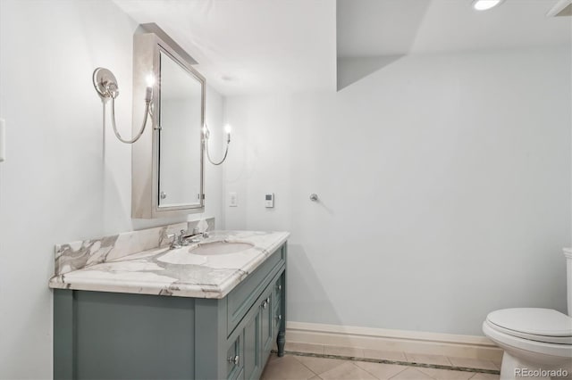 half bath with toilet, vanity, baseboards, and tile patterned floors