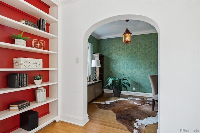 interior space with wallpapered walls, baseboards, ornamental molding, and wood finished floors