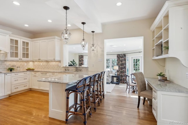 kitchen featuring hanging light fixtures, light wood-style floors, a breakfast bar, and a sink