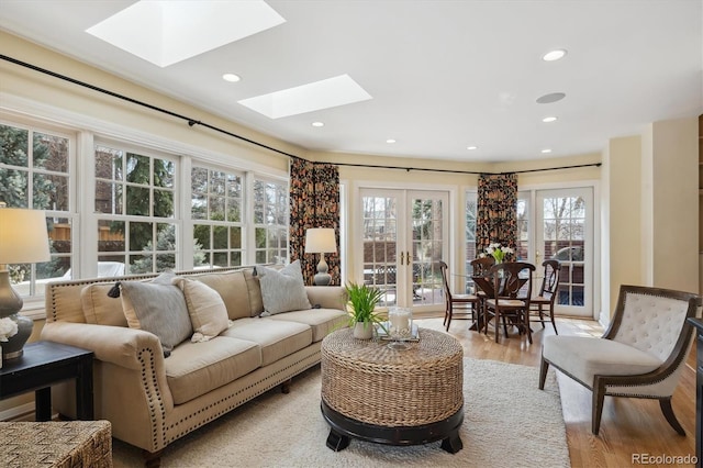 living room with light wood-type flooring, a skylight, french doors, and recessed lighting