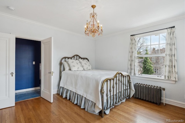 bedroom with radiator heating unit, crown molding, baseboards, and wood finished floors