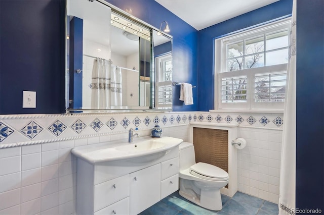 bathroom with curtained shower, toilet, vanity, tile walls, and tile patterned floors