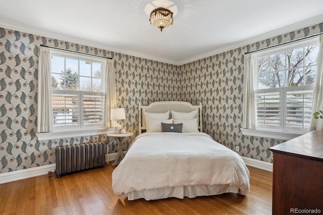 bedroom with wallpapered walls, baseboards, radiator heating unit, wood finished floors, and crown molding