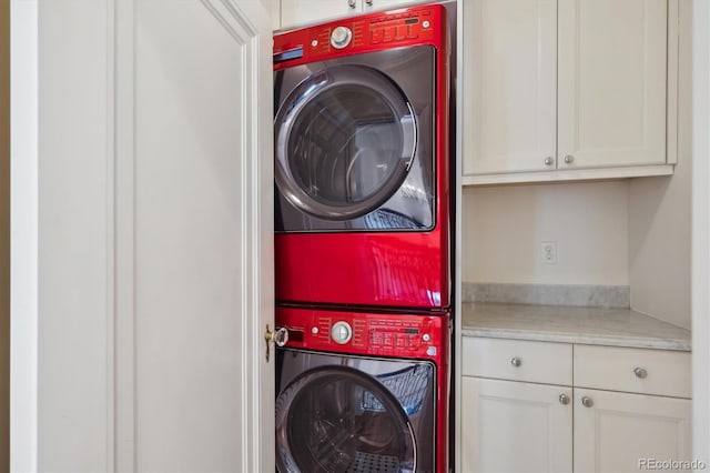 washroom with cabinet space and stacked washer and clothes dryer