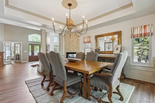 9880 E Progress Cir, Greenwood Village, CO 80111 - dining space featuring a raised ceiling, a chandelier, ornamental molding, wood finished floors, and a multi sided fireplace