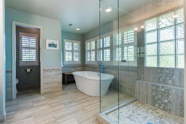 9880 E Progress Cir, Greenwood Village, CO 80111 - bathroom with tile walls, a soaking tub, tiled shower, toilet, and a wainscoted wall