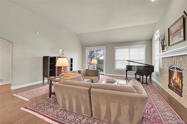 living area with lofted ceiling, a fireplace, wood finished floors, and baseboards