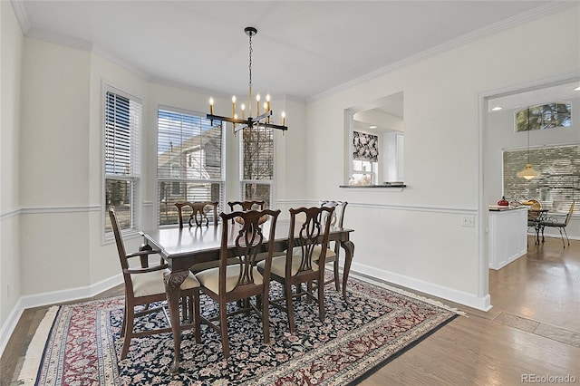 dining space with crown molding, baseboards, wood finished floors, and an inviting chandelier