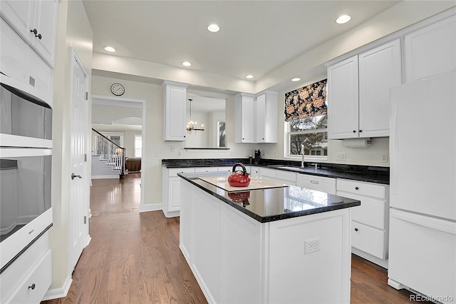 kitchen featuring dark wood finished floors, dark countertops, freestanding refrigerator, white cabinets, and a kitchen island