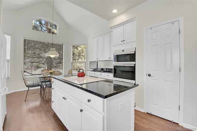 kitchen with white cabinets, lofted ceiling, a kitchen island, wood finished floors, and hanging light fixtures