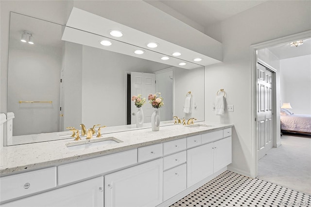 ensuite bathroom with a sink, double vanity, connected bathroom, and recessed lighting