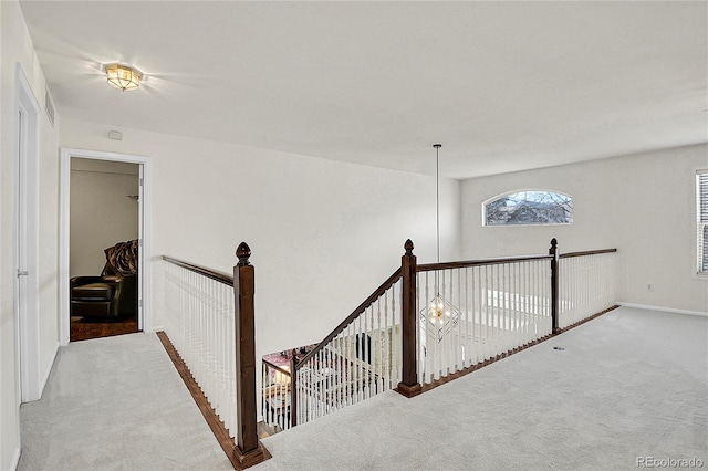 hall with an upstairs landing and light colored carpet