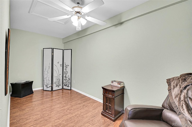 sitting room featuring light wood-style floors, attic access, baseboards, and a ceiling fan