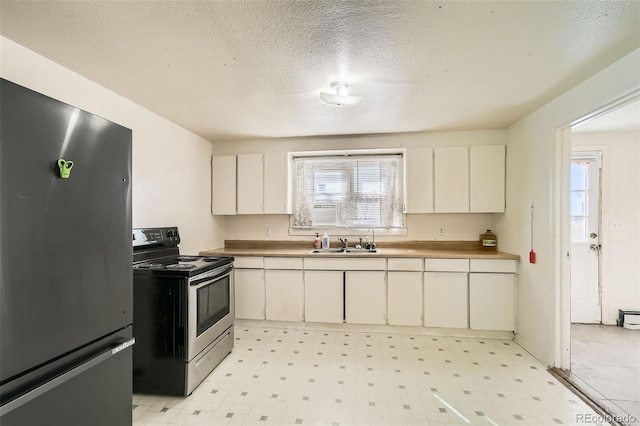 kitchen with appliances with stainless steel finishes, baseboard heating, a textured ceiling, light floors, and a sink