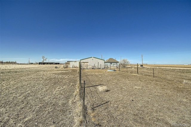 view of yard featuring an outbuilding, a pole building, a rural view, and fence