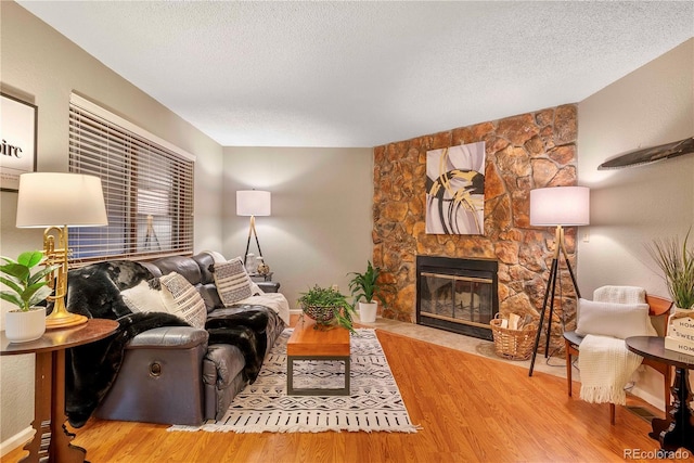 living area featuring a fireplace, a textured ceiling, and wood finished floors