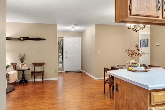foyer entrance featuring light wood-type flooring, an inviting chandelier, and baseboards