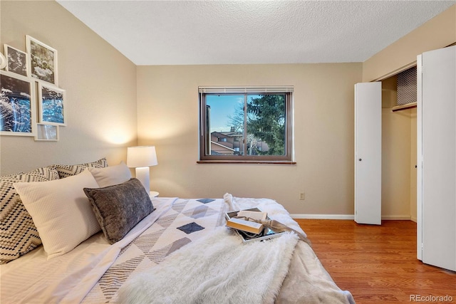 bedroom featuring baseboards, a textured ceiling, and wood finished floors