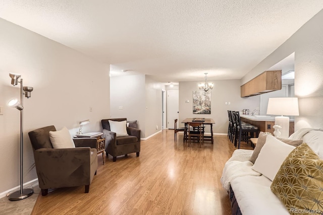 9411 W 89th Cir, Westminster, CO 80021 - living room featuring a textured ceiling, a chandelier, light wood-type flooring, and baseboards