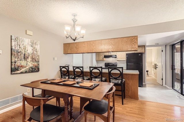 9411 W 89th Cir, Westminster, CO 80021 - dining room featuring a chandelier, a textured ceiling, light wood-type flooring, and baseboards