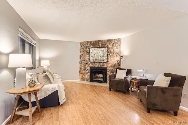 9411 W 89th Cir, Westminster, CO 80021 - living area with light wood finished floors, a stone fireplace, a textured ceiling, and baseboards