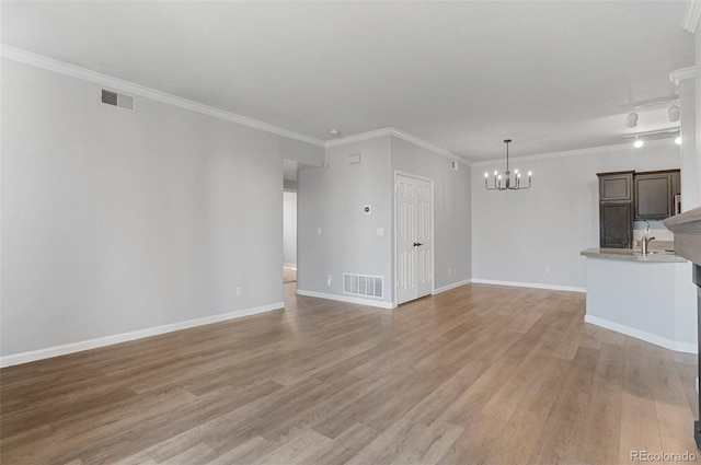 unfurnished living room with light wood-type flooring, an inviting chandelier, and ornamental molding