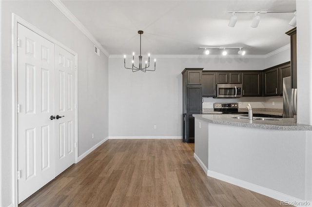 kitchen with hanging light fixtures, sink, ornamental molding, appliances with stainless steel finishes, and dark brown cabinets