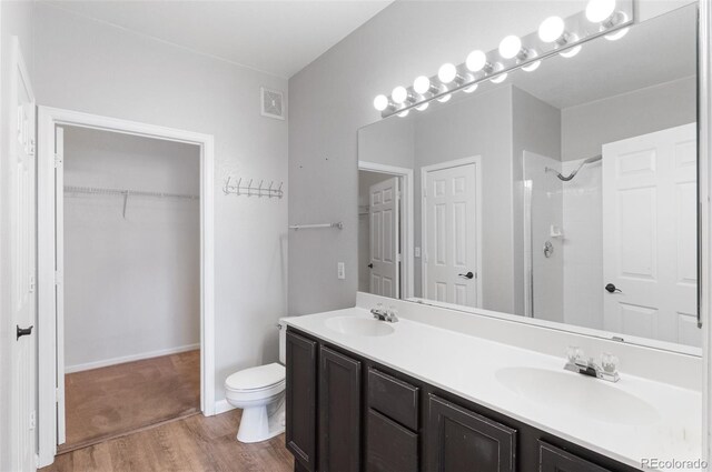 bathroom featuring wood-type flooring, vanity, toilet, and walk in shower