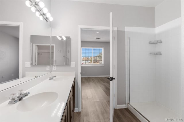 bathroom featuring tiled shower, wood-type flooring, and vanity