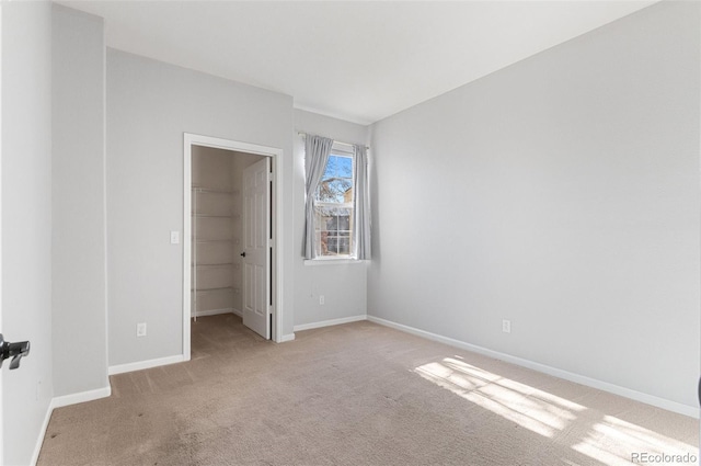 unfurnished bedroom with light colored carpet, a spacious closet, and a closet