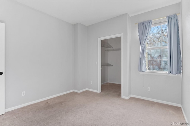 unfurnished bedroom featuring a spacious closet, a closet, and light colored carpet