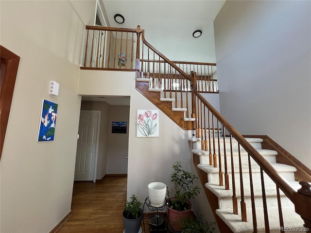 stairs with a high ceiling and wood-type flooring