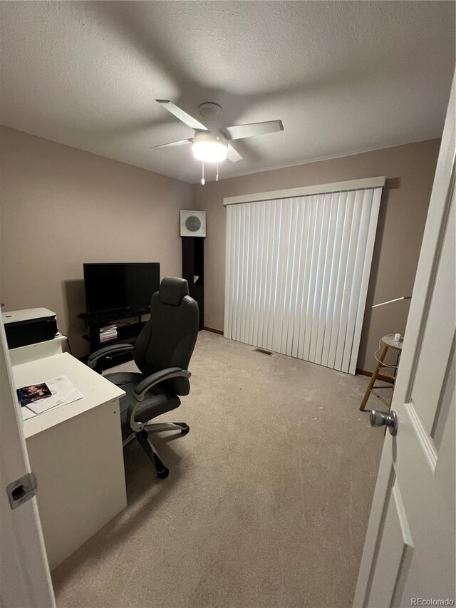 office area featuring a textured ceiling, ceiling fan, and light colored carpet