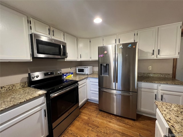 kitchen featuring appliances with stainless steel finishes, light stone counters, dark wood-type flooring, and white cabinets