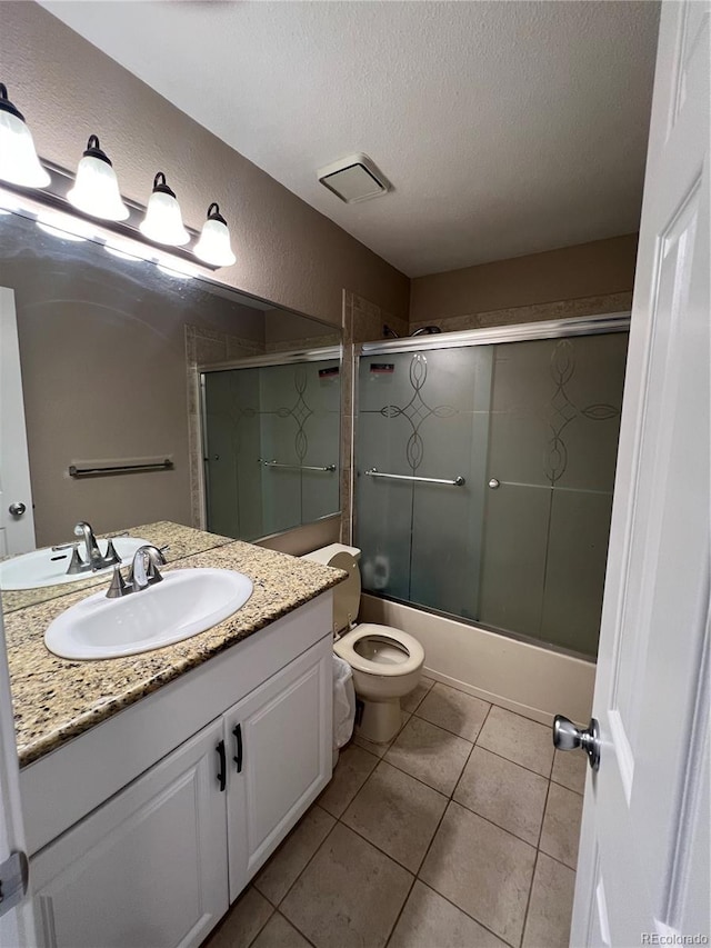 full bathroom featuring shower / bath combination with glass door, vanity, a textured ceiling, tile patterned floors, and toilet