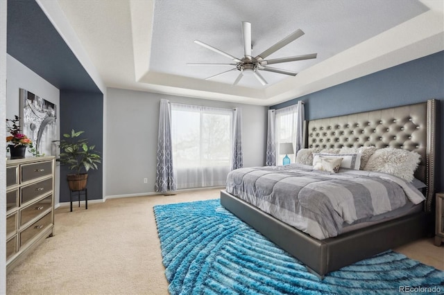 carpeted bedroom featuring ceiling fan, a tray ceiling, and a textured ceiling