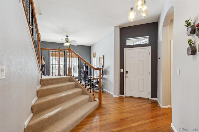 10251 Rifle St, Commerce City, CO 80022 - foyer featuring stairway, a ceiling fan, wood finished floors, baseboards, and arched walkways