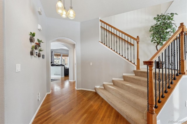 10251 Rifle St, Commerce City, CO 80022 - stairs featuring arched walkways, a notable chandelier, baseboards, and wood finished floors