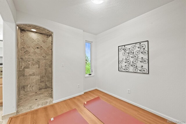 10235 Rustic Redwood Ln, Highlands Ranch, CO 80126 - exercise room featuring light wood finished floors, baseboards, and a textured ceiling