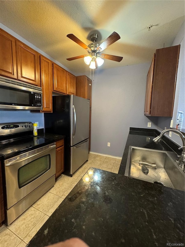 kitchen featuring dark countertops, light tile patterned floors, appliances with stainless steel finishes, and a textured ceiling