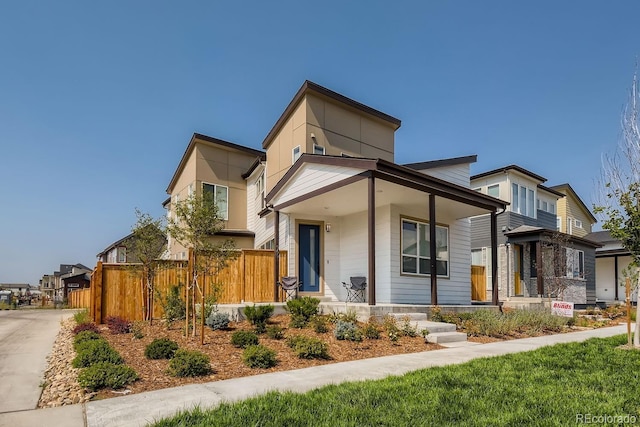 contemporary home with covered porch and fence