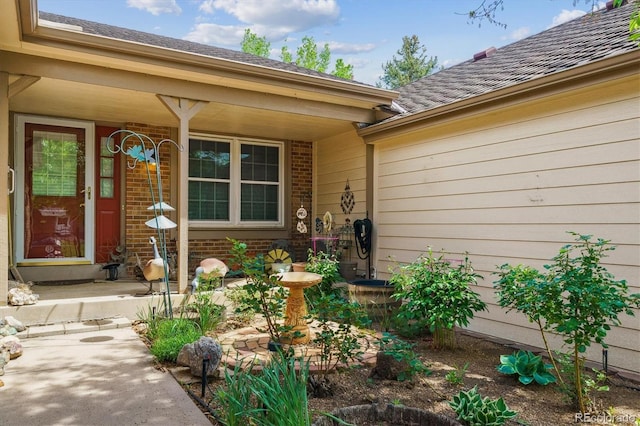 6143 E Hinsdale Ave, Centennial, CO 80112 - doorway to property featuring brick siding, a porch, and roof with shingles