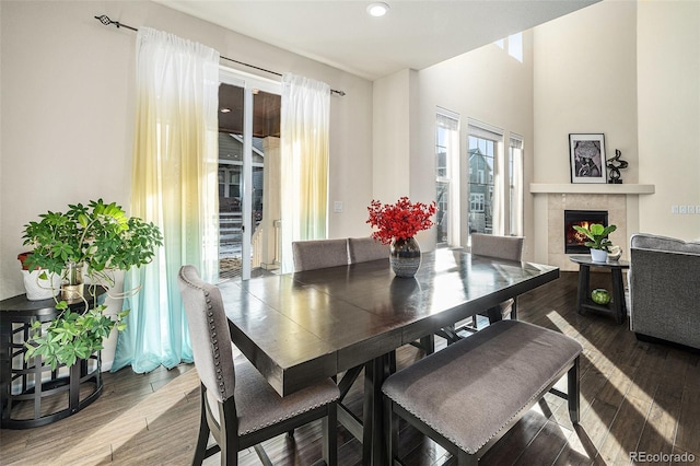 dining room with recessed lighting, wood finished floors, and a warm lit fireplace