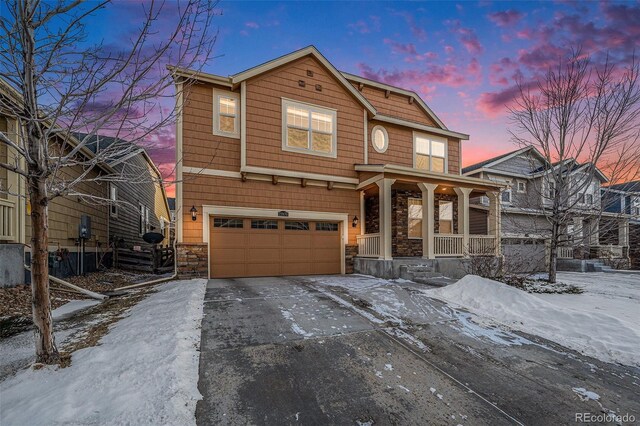 view of front of property with a porch, driveway, stone siding, and a garage