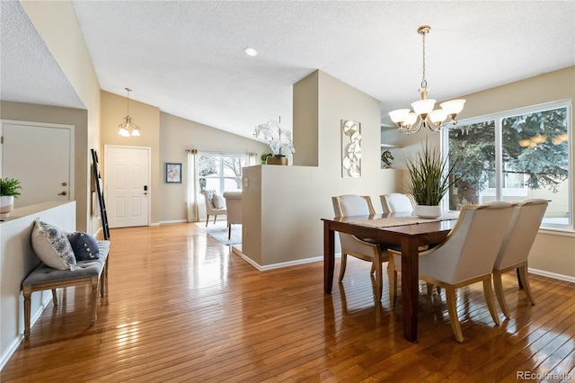 dining space with light hardwood / wood-style floors, a healthy amount of sunlight, lofted ceiling, and an inviting chandelier